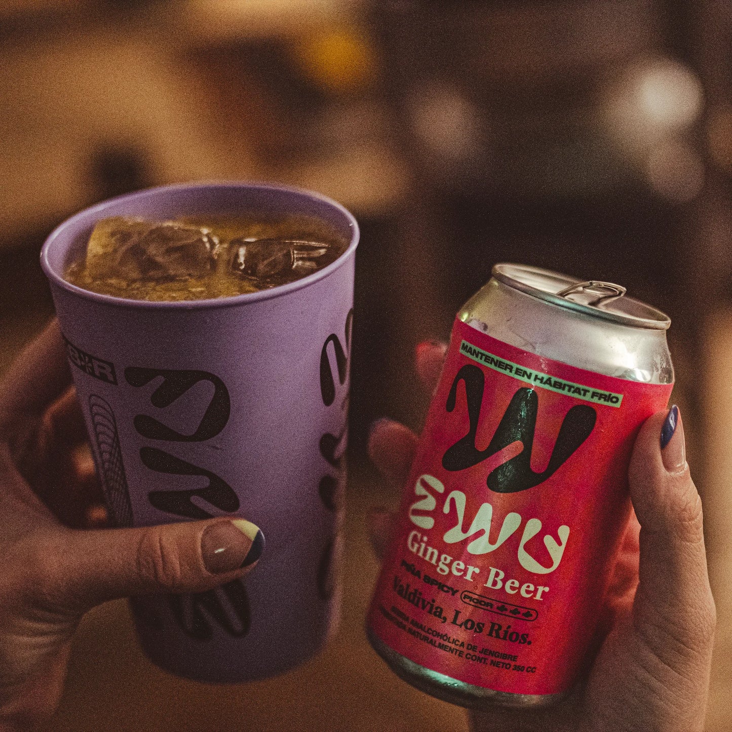 Lata de EWU Ginger Beer Piña Spicy junto a un cóctel en un bar